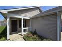 A cozy front porch with white pillars leading to the home's front door and a small window at 5609 Sweet River Dr, Indianapolis, IN 46221