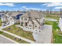 Aerial view showcasing a brick home, extended driveway, landscaping and the surrounding community pond at 6044 Shallow Crk Ln, Indianapolis, IN 46237