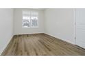Well-lit bedroom showcases wood-look flooring, a large window, and neutral paint for a cozy feel at 6474 Ambassador Dr, Plainfield, IN 46168