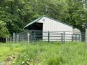Exterior view of a metal Morton barn with a green metal roof and fenced enclosure surrounded by lush trees and field at 685 N Buffalo Hill Rd, Martinsville, IN 46151