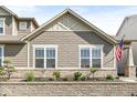 Home featuring decorative siding, landscaping, a stone retaining wall, and an American flag at 7092 Cherry Creek Blvd, Carmel, IN 46033