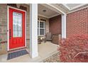 Inviting front porch with a red door, decorative plants, and seating area with great curb appeal at 7450 Cassilly Ct, Indianapolis, IN 46278
