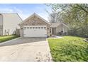A well-maintained brick home featuring an attached garage, a welcoming entrance, and a lush green lawn at 7841 Whitaker Farms Ln, Indianapolis, IN 46237