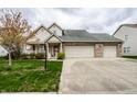 Traditional two-story home featuring a three-car garage, complemented by a lush front yard and mature trees at 8618 Turnstone Ct, Indianapolis, IN 46234