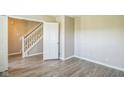 Bright, neutral room with wood-look flooring, white trim, and open doorway to staircase at 8888 N White Tail N Trl, McCordsville, IN 46055