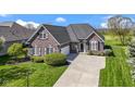 Charming brick home with a manicured lawn, mature trees, and a spacious driveway leading to a garage at 10911 Innisbrooke Ln, Fishers, IN 46037