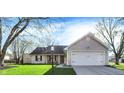 Inviting single-story home with attached two-car garage, featuring a well-manicured lawn and mature trees at 12005 Hardwick Dr, Fishers, IN 46038
