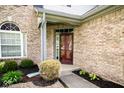 Close-up of the front entrance featuring a brick facade, lush landscaping, and a modern front door for a welcoming feel at 13331 Grouse Point Trl, Carmel, IN 46033