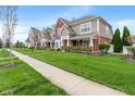 Attractive townhomes lining a street with green lawns, sidewalks, and young trees at 1352 Middlebury Dr, Westfield, IN 46074