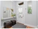 Bright foyer showcasing a decorative front door, modern mirror, and stylish bench seating at 1453 English Ave, Indianapolis, IN 46201