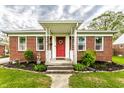 Inviting front porch with white railing, red door, and nicely landscaped garden bed at 1733 N Spencer Ave, Indianapolis, IN 46218