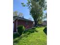 The backyard featuring a well-kept lawn, lush greenery, and mature trees at 2141 N Cole St, Indianapolis, IN 46224