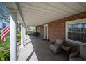 Relax on the inviting covered porch with ample seating, classic brickwork, and an American flag at 2394 W 600 S, New Palestine, IN 46163