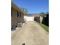 Exterior shot of a driveway leading to a detached garage with a white door at 263 Clark Ave, Beech Grove, IN 46107