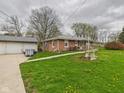 Brick home with a detached two-car garage and a spacious yard full of dandelions at 306 W Clyde St, Frankton, IN 46044