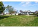 Expansive front yard of the property, featuring a well-kept lawn, detached garage, and mature trees at 3737 Forest Ter, Anderson, IN 46013