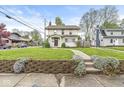 Quaint home with a stone foundation and walkway bordered by purple flowers at 4575 N Guilford Ave, Indianapolis, IN 46205