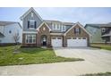 Charming two-story home with brick and gray siding, attached two-car garage, and well-manicured lawn at 613 Waterford Ln, Westfield, IN 46074