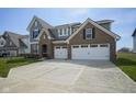 Charming two-story home with brick and gray siding, attached two-car garage, and well-manicured lawn at 613 Waterford Ln, Westfield, IN 46074