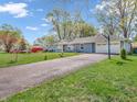 The front of this home features a long driveway, two-car garage, and a well-maintained lawn with mature trees at 7671 Sherry Ln, Brownsburg, IN 46112