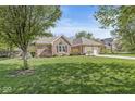 Brick house with mature trees, a well-manicured lawn, and a driveway leading to an attached garage at 768 Grace Ct, Carmel, IN 46032