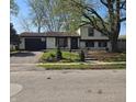 Charming home with a well-manicured lawn, mature trees, and an attached garage at 8041 Barry Rd, Indianapolis, IN 46219