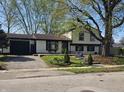 Inviting home featuring mature trees, manicured lawn, and an attached garage at 8041 Barry Rd, Indianapolis, IN 46219