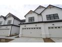 Townhome featuring white exterior, black trim, two-car garage, and natural wood accents on roof peaks at 17458 Ebling Trl, Westfield, IN 46062