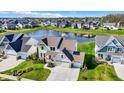 An aerial view of a neighborhood with a pond and fountain surrounded by well-maintained homes at 180 Oakhurst Way, Westfield, IN 46074