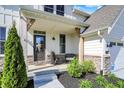 Inviting front porch with stone accents, a black door, and stylish landscaping at 180 Oakhurst Way, Westfield, IN 46074
