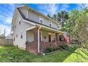 Charming two-story home featuring a front porch with red brick columns and an American flag at 207 S Arlington Ave, Indianapolis, IN 46219
