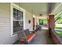 Spacious covered front porch with a wooden swing, red brick columns, and neutral siding at 207 S Arlington Ave, Indianapolis, IN 46219