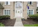 Close-up of the front door entrance, featuring sidelights, a wreath, and brick facade at 3837 Penzance Pl, Carmel, IN 46032