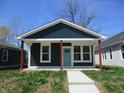 Charming home featuring a blue front door, red pillars, and well-maintained lawn at 4230 Kingsley Dr, Indianapolis, IN 46205