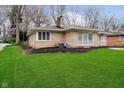 A view of the rear of the house with green lawn and mature trees at 5715 N Meridian St, Indianapolis, IN 46208