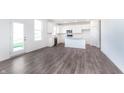 Bright, open-concept kitchen with stainless steel appliances, white cabinetry, and gray wood flooring at 6801 Seabiscuit Rd, Whitestown, IN 46075