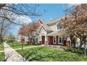 Exterior view of townhomes with brick facades, covered porches, landscaped lawns, and a sidewalk at 720 Bucksport Ln, Westfield, IN 46074