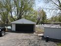 View of a detached garage with black door and a shed behind with white fence at 1029 Price Rd, Avon, IN 46123