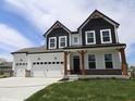 Two-story home showcasing a three-car garage and stylish black and white color scheme at 1114 Ridgevine Rd, Greenwood, IN 46143
