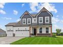 Striking two-story home with a three car garage, craftsman details and a well-manicured lawn at 1114 Ridgevine Rd, Greenwood, IN 46143