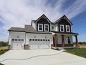 Two-story home showcasing a three-car garage and stylish black and white color scheme at 1114 Ridgevine Rd, Greenwood, IN 46143