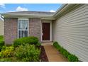 Home featuring a brick exterior, complemented by lush landscaping and a warm, inviting entryway at 2138 Rossington Ln, Indianapolis, IN 46229