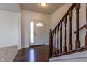 Bright entryway featuring hardwood floors, a white front door with glass accents, and staircase with wooden railing at 2545 Coneflower Ct, Columbus, IN 47201