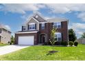 Charming two-story brick home with manicured lawn, and a two car garage under a cloudy blue sky at 2545 Coneflower Ct, Columbus, IN 47201