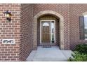 Inviting front entrance with a stylish, dark wood door and beautiful brick archway, and green landscaping at 2545 Coneflower Ct, Columbus, IN 47201