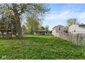 Expansive backyard with lush grass, mature trees, and play structure offer ample space for recreation at 2822 Walker Ave, Indianapolis, IN 46203