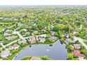 An aerial view of a peaceful residential area with homes surrounding a serene pond at 3790 Steeplechase Dr, Carmel, IN 46032