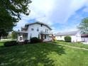 Charming two-story house with a cozy front porch, lush greenery, and a detached garage, perfect for outdoor enjoyment at 4335 River Rd, Columbus, IN 47203