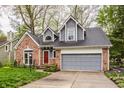 Charming home with brick and gray facade, featuring a well-manicured lawn and attached garage at 5467 Winterhazel Dr, Indianapolis, IN 46254