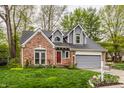 Attractive two-story home featuring a brick facade, gray roof, attached garage, and a well-manicured front lawn at 5467 Winterhazel Dr, Indianapolis, IN 46254